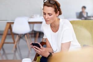 Busy business woman in office reads emails on her smartphone device